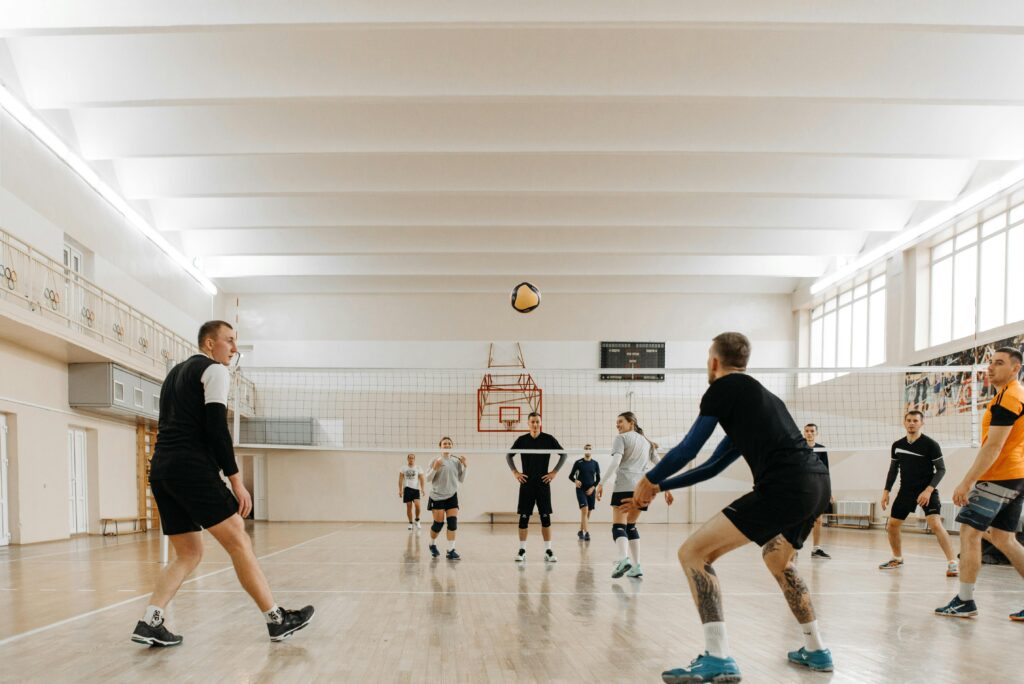Players engaged in an exciting indoor volleyball game on a wooden floor court.