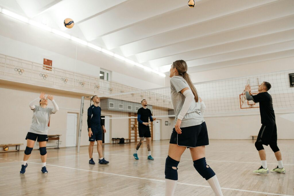 Group of adults playing volleyball indoors, focused on teamwork and action.