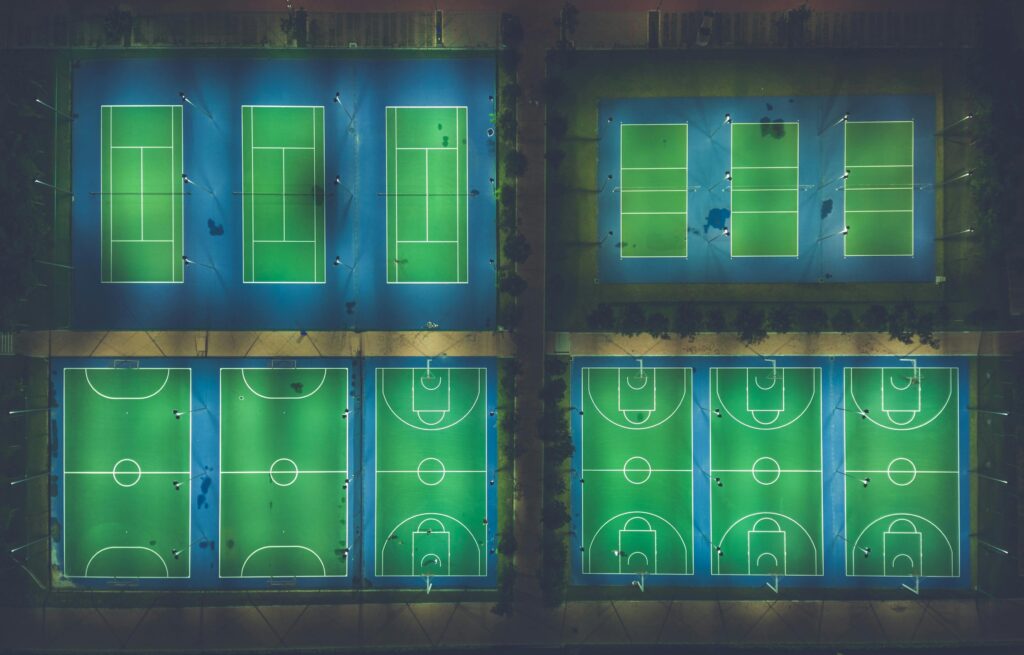 A captivating aerial view of illuminated sports courts at night showcasing patterns and symmetry.